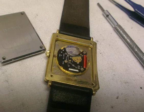 Geöffnete Armbanduhr mit Schraubendreher und Pinzette